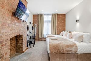a bedroom with a large bed and a brick fireplace at The Stuart Hotel in Liverpool