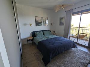 a bedroom with a blue bed and a balcony at U Flenu sea view in San-Martino-di-Lota