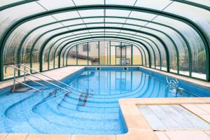 a large swimming pool with a glass ceiling at L'orée du bois in Yenne