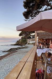 a beach with people sitting at a table with an umbrella at U Flenu sea view in San-Martino-di-Lota