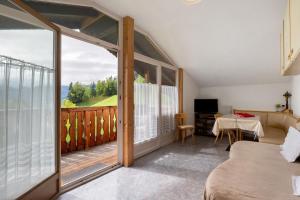 a room with a bed and a balcony with a view at Mittermüllerhof Feldthurns in Velturno