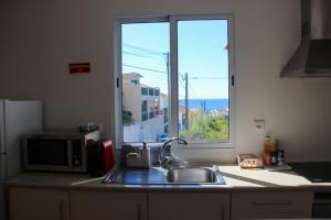 a kitchen counter with a sink and a window at A m a r - 450m from the beach in São Roque