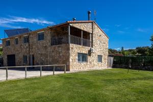 a stone building with a grass yard in front of it at La Nave de Gredos in Burgohondo