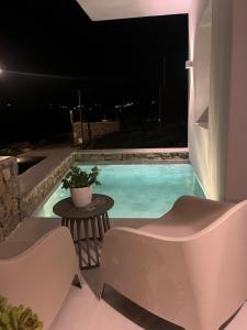 a swimming pool at night with a table and chairs at Eidolion Essence - Mykonos Villa with Private Pool in Ano Mera