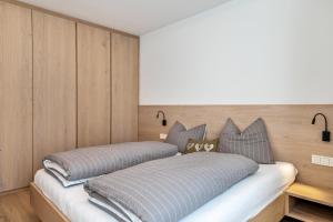 two beds in a room with wooden walls at Mountain Meadows Apt 3 in Valdaora