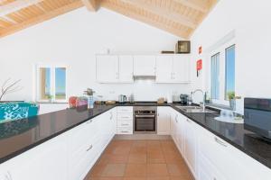a kitchen with white cabinets and black counter tops at Paraiso da Serva - Courela da Serva in Odemira