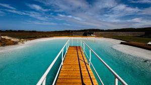 a large pool of blue water with a wooden boardwalk at Paraiso da Serva - Courela da Serva in Odemira