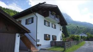 a large white building with a porch and a bench at Ferienwohnung Kramerblick in Grainau +5 photos