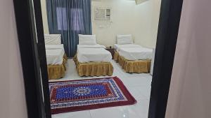 a room with three beds and a rug and a mirror at عمارة دار الضيافة in Medina