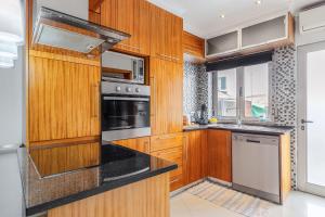 a kitchen with wooden cabinets and a stove top oven at Vista Das Estrelas M4 - Terceira in Praia da Vitória