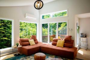 a living room with two brown couches and windows at Chalet Victoria - Private Spa & Nature in Pont-Rouge