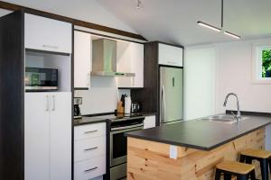 a kitchen with white cabinets and a black counter top at Chalet Victoria - Private Spa & Nature in Pont-Rouge +29 photos
