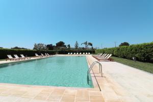 a large swimming pool with lounge chairs and trees at Bungalow Italia in Otranto