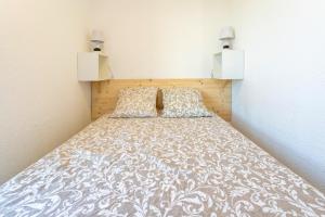 a bed in a bedroom with two lights on the wall at Evasion Atlantique, accès plage in Capbreton