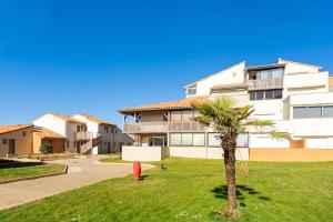 a building with a palm tree and a fire hydrant at Evasion Atlantique, accès plage in Capbreton