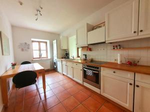 a kitchen with white cabinets and a table and a stove at Schöne Wohnung Landhaus-Flair in Aachen