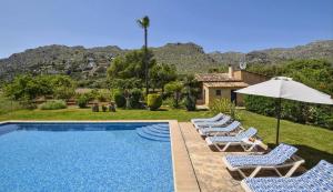 a villa with a swimming pool with chairs and an umbrella at Tonina in Pollença