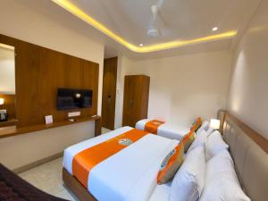 a hotel room with a bed and a tv at Hotel Neem Heritage in Shirdi