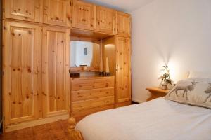 a bedroom with a wooden cabinet and a bed at Appartamento Eva in Folgaria