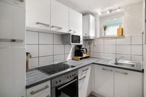 a white kitchen with a sink and a microwave at Ferienwohnung Alpensicht in Oberteuringen