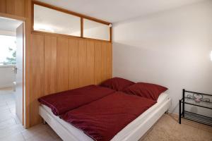 a bedroom with a bed with a red comforter at Ferienwohnung Alpensicht in Oberteuringen +17 photos