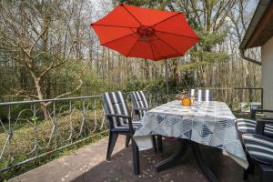 a table and chairs with a red umbrella on a porch at Baumfuchs Ferienbungalow in Wesenberg +13 photos
