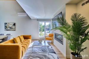 a living room with a couch and a plant at Villa Boreale - Private Spa Pool & Foosball in Valcartier Station