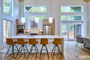 a kitchen with a large white island with bar stools at Villa Boreale - Private Spa Pool & Foosball in Valcartier Station