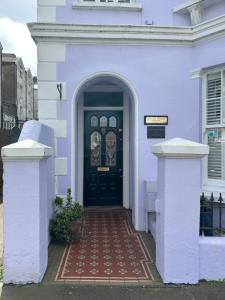 a white house with a black door and a red brick walkway at Gyves House in Eastbourne +6 photos