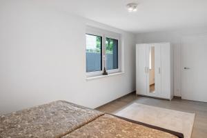 a white room with a bed and two windows at Schönes Apartment am Kaiserstuhl in Bahlingen