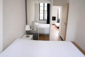 a bedroom with a white bed and a mirror at Logement entier rue Sainte Catherine in Bordeaux