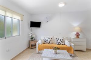 a white living room with a couch and a tv at Apartamento Danoe 4 in Mogán