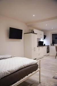 a white bedroom with a bed and a kitchen at Ferienwohnung in Pfullendorf