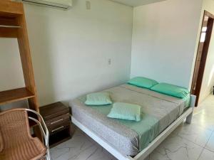 a bedroom with a bed with green pillows and a chair at Residencial Esmeralda-Vista ao Mar in Palhoça
