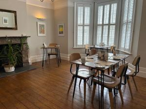 a dining room with a table and chairs and a fireplace at Gyves House in Eastbourne
