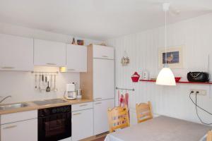 a small kitchen with white cabinets and a table and a tableablish at Möve Aba Bungalow 62 in Rerik +15 photos