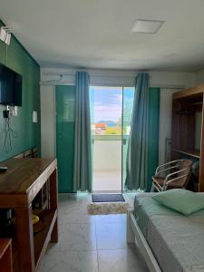 a bedroom with a bed and a sliding glass door at Residencial Esmeralda-Vista ao Mar in Palhoça