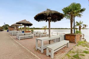 a row of white benches and umbrellas next to the water at Speicherhäuschen Maike in Geeste