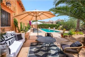 a patio with a table and an umbrella next to a pool at El Palomar in Santanyi