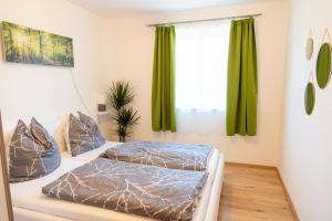 two beds in a bedroom with green curtains at Knollgut Ferienwohnung Buchberg in Goldegg