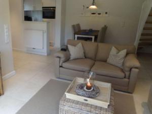 a living room with a couch and a candle on a table at Sylthus-Haithabu in Wenningstedt +8 photos