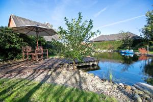 a wooden deck with an umbrella and chairs next to a river at Holzhaus Grimm in Fedderingen