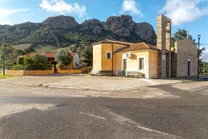 a small yellow building with a mountain in the background at Casa Michela in Viddalba