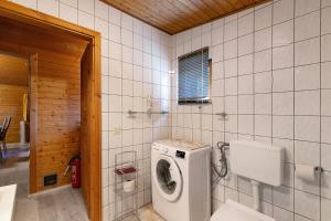 a bathroom with a washing machine in a tiled wall at Holzhaus Grimm in Fedderingen +18 photos