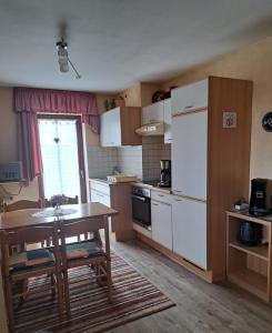 a kitchen with a table and a white refrigerator at Pension Andrea in Herbstein