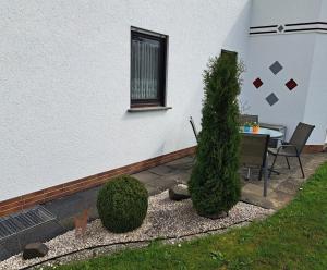 a patio with a table and a tree next to a building at Pension Andrea in Herbstein