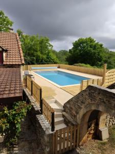 a swimming pool with a wooden bridge next to a house at Mas De Palaille, Piscine et Nature in Salvagnac-Cajarc