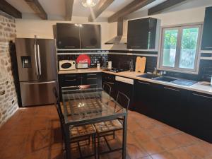 a kitchen with black cabinets and stainless steel appliances at Mas De Palaille, Piscine et Nature in Salvagnac-Cajarc +5 photos