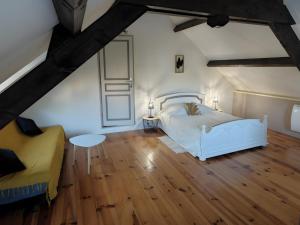a bedroom with a white bed and a yellow couch at Mas De Palaille, Piscine et Nature in Salvagnac-Cajarc