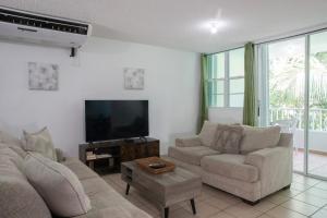 a living room with a couch and a flat screen tv at Landing View 204 with private rooftop terrace in Rincon